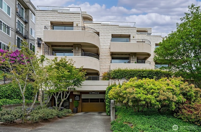 view of apartment building / complex with asphalt driveway and a garage