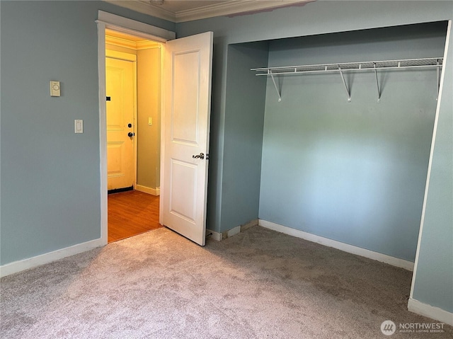 unfurnished bedroom featuring carpet floors, a closet, baseboards, and ornamental molding
