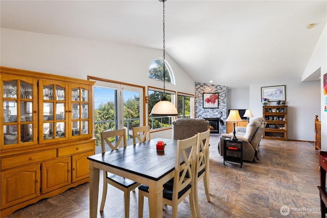 dining room featuring a fireplace and high vaulted ceiling
