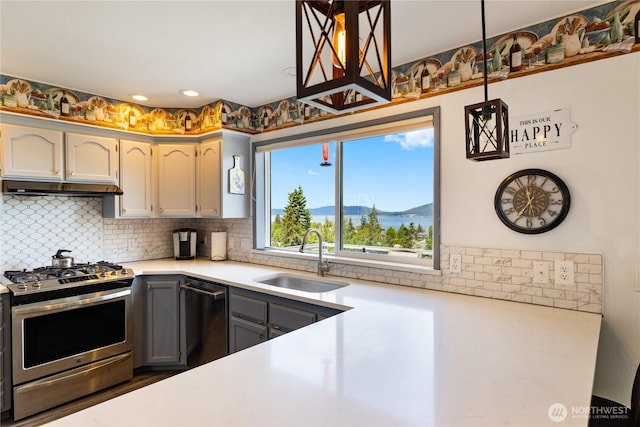 kitchen with appliances with stainless steel finishes, a sink, tasteful backsplash, light countertops, and under cabinet range hood