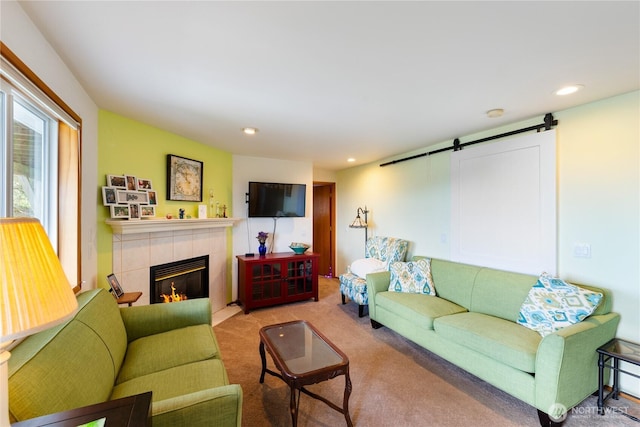 carpeted living room with a barn door, a tiled fireplace, and recessed lighting