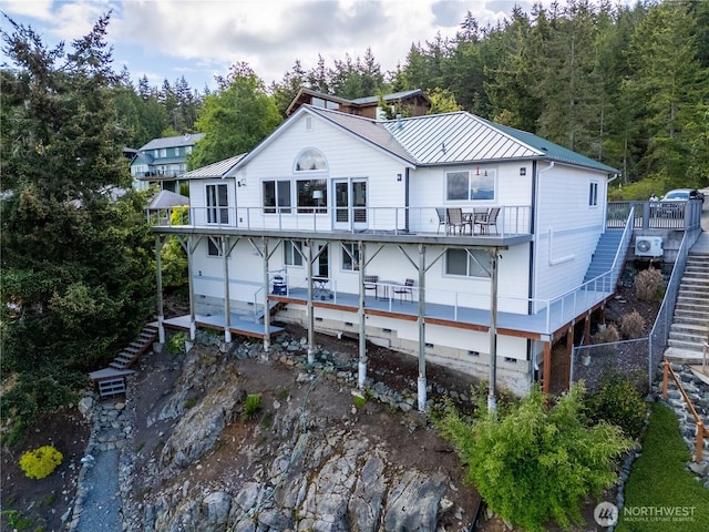 rear view of property with stairs, a standing seam roof, metal roof, and a balcony