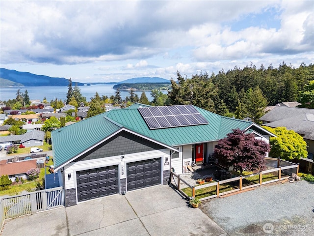 view of front of house with a water and mountain view, a garage, a gate, driveway, and roof mounted solar panels