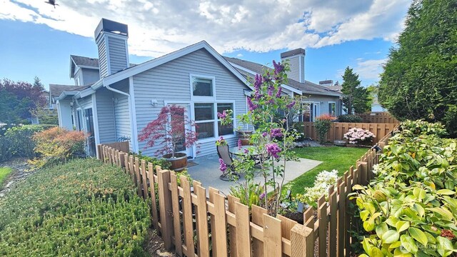 rear view of property featuring a chimney, fence, and a patio area