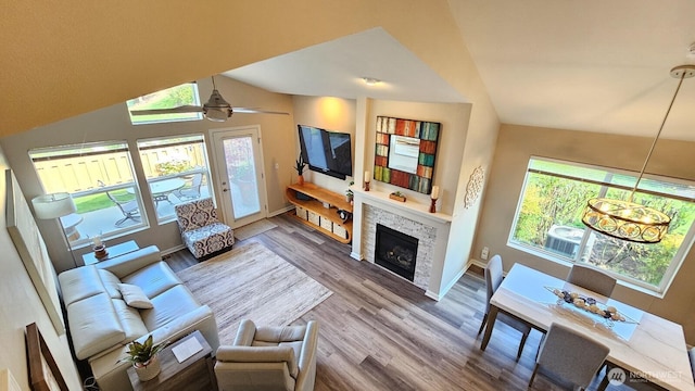 living room featuring wood finished floors, plenty of natural light, a fireplace, vaulted ceiling, and baseboards