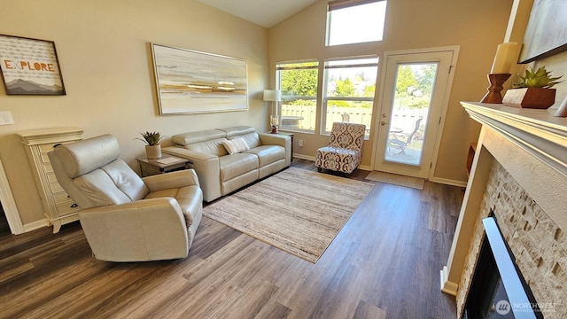 living area with a fireplace, lofted ceiling, wood finished floors, and baseboards