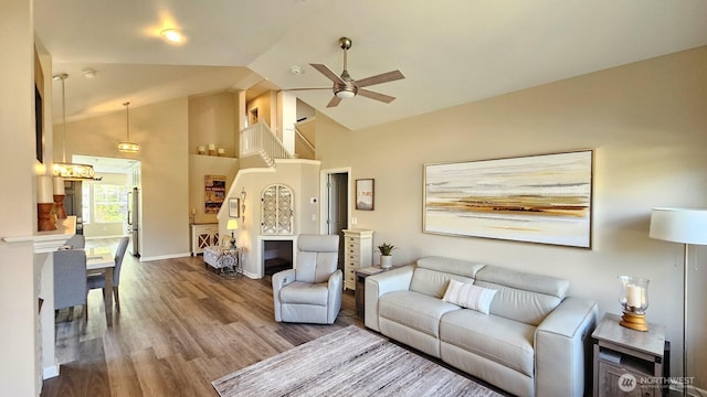 living area featuring ceiling fan, high vaulted ceiling, wood finished floors, and baseboards