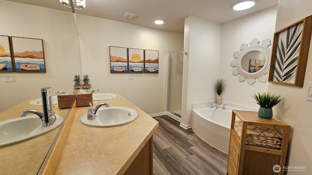 bathroom featuring wood finished floors, double vanity, a stall shower, and a garden tub