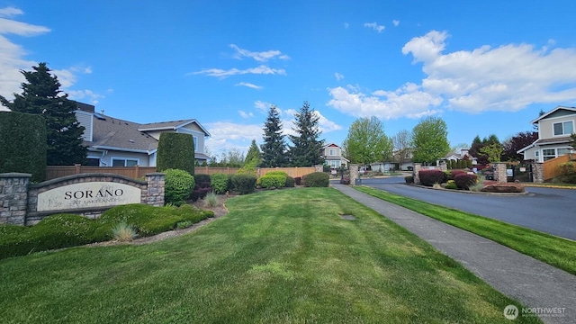 view of asphalt road with sidewalks, a residential view, curbs, and a gated entry
