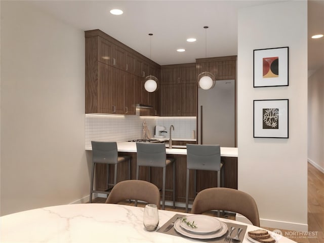 kitchen with light countertops, tasteful backsplash, a peninsula, recessed lighting, and light wood-style flooring