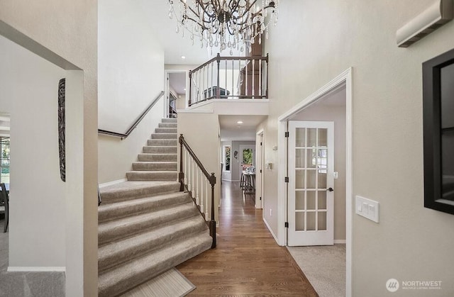 entryway featuring plenty of natural light, stairway, baseboards, and a high ceiling