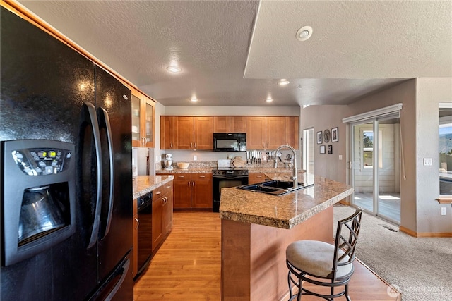 2541 Fancher Heights Blvd, East Wenatchee, WA 98802 - kitchen with black appliances, a sink, a textured ceiling, light wood-style floors, and brown cabinetry
