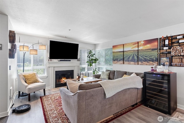 3908 243rd Pl SE Unit Q-203, Bothell, WA 98021 - living area featuring beverage cooler, wood finished floors, healthy amount of natural light, and a glass covered fireplace
