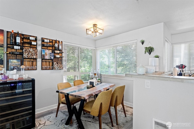 3908 243rd Pl SE Unit Q-203, Bothell, WA 98021 - dining room featuring wine cooler, a chandelier, wood finished floors, and baseboards