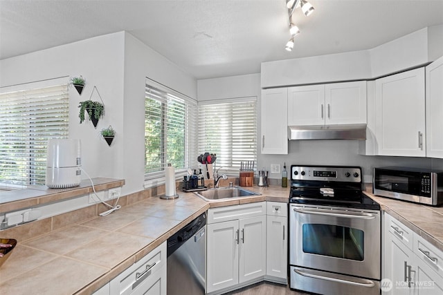 3908 243rd Pl SE Unit Q-203, Bothell, WA 98021 - kitchen with appliances with stainless steel finishes, under cabinet range hood, tile counters, a sink, and white cabinetry