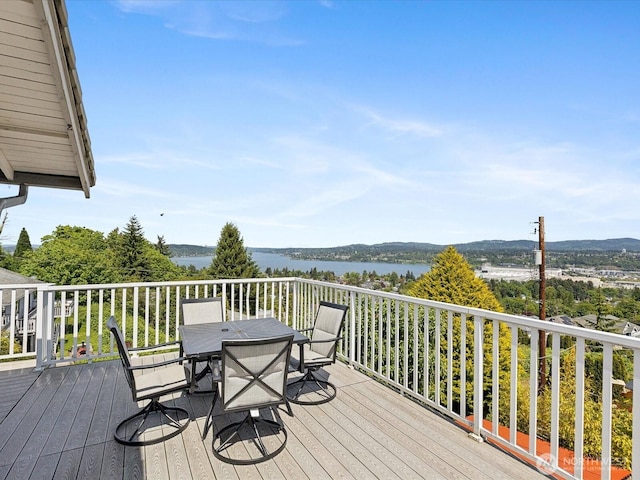deck with outdoor dining area and a water view