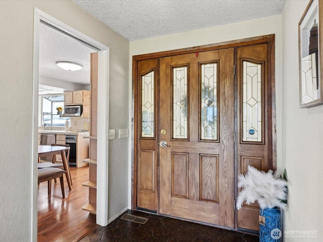 foyer featuring a textured ceiling and baseboards