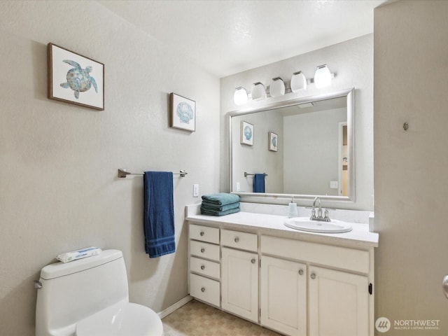 half bathroom featuring toilet, vanity, and baseboards