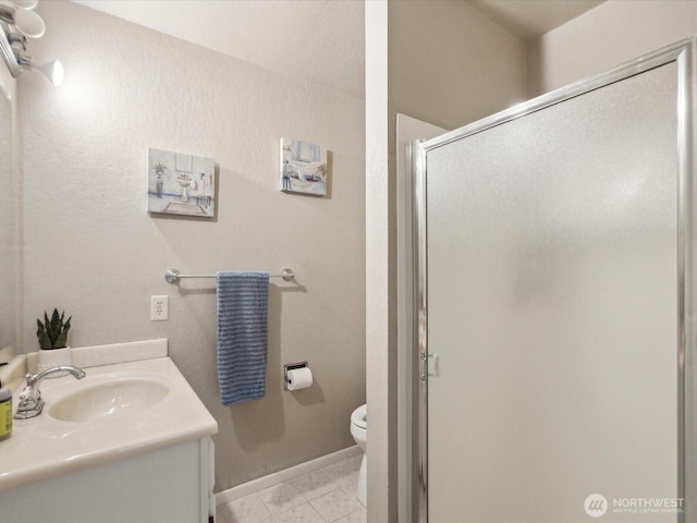 full bath featuring a shower stall, toilet, vanity, and baseboards