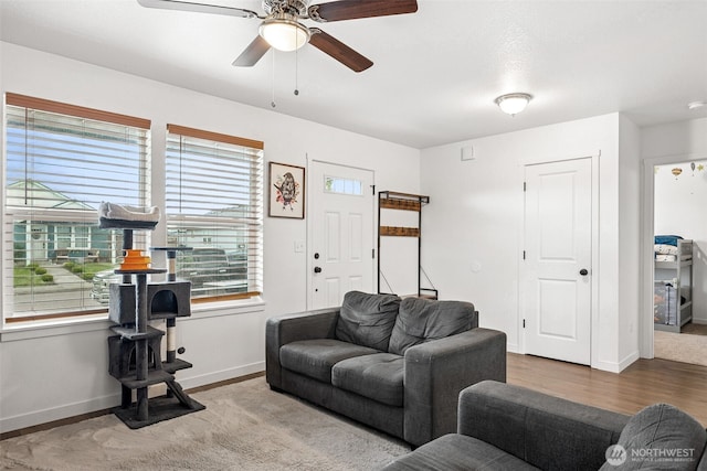 living area featuring a ceiling fan, baseboards, and wood finished floors