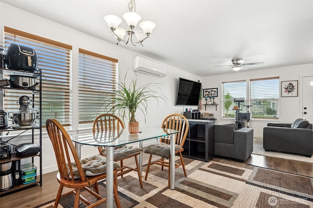 dining room featuring wood finished floors, an AC wall unit, a chandelier, and ceiling fan