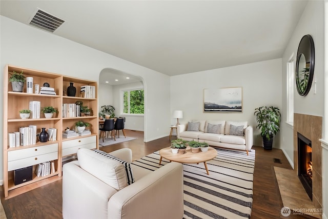 18910 SE 41st Dr, Vancouver, WA 98683 - living room featuring dark wood-style flooring, a fireplace with flush hearth, arched walkways, and baseboards