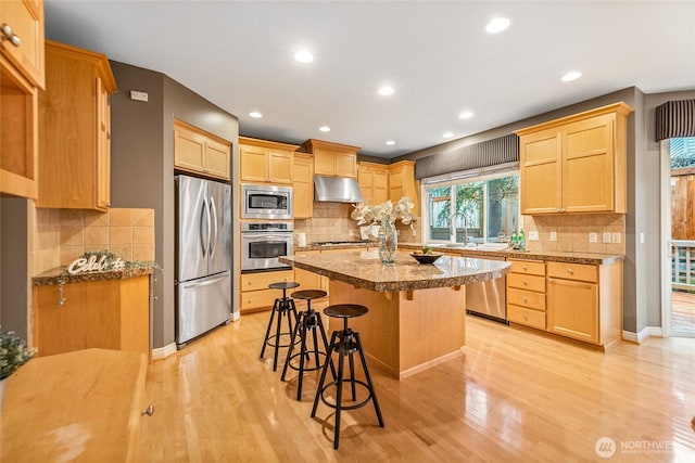 908 274th Way SE, Sammamish, WA 98075 - kitchen featuring stainless steel appliances, under cabinet range hood, a kitchen bar, light wood finished floors, and recessed lighting