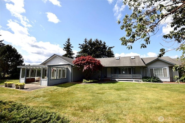 rear view of house with a lawn, a sunroom, and a porch