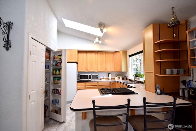 kitchen featuring stainless steel microwave, light brown cabinets, stovetop, lofted ceiling, and a peninsula