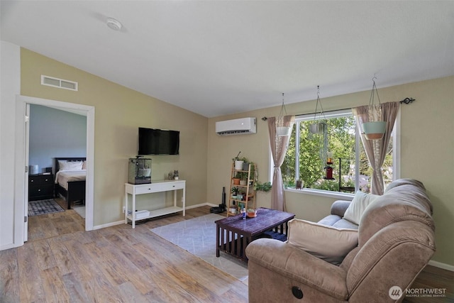 living area featuring an AC wall unit, wood finished floors, vaulted ceiling, and baseboards