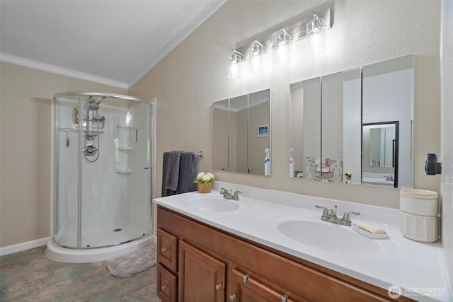 bathroom with ornamental molding, a shower stall, double vanity, and baseboards