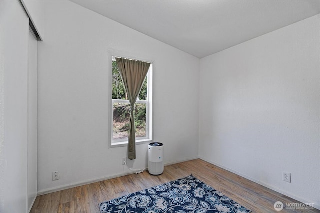 spare room with lofted ceiling, wood finished floors, and baseboards