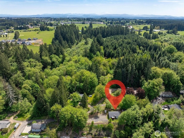 aerial view of property and surrounding area with a mountain backdrop and a heavily wooded area