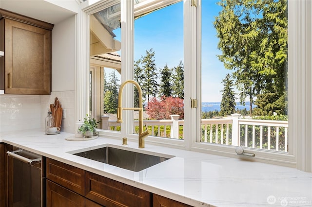 9416 NE 25th St, Clyde Hill, WA 98004 - kitchen featuring a sink, decorative backsplash, light stone countertops, stainless steel dishwasher, and healthy amount of natural light