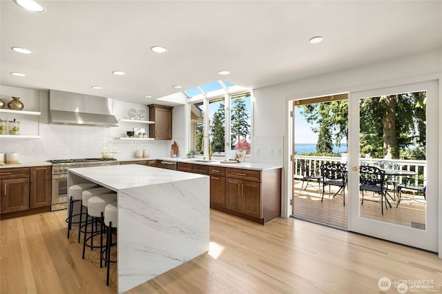 9416 NE 25th St, Clyde Hill, WA 98004 - kitchen with open shelves, wall chimney exhaust hood, high end stainless steel range, a sink, and tasteful backsplash