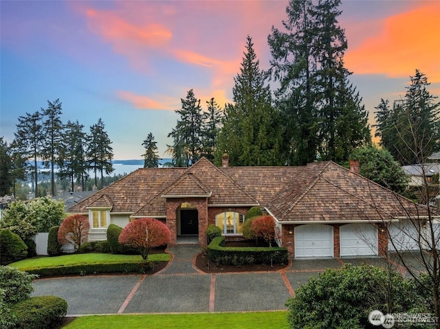 9416 NE 25th St, Clyde Hill, WA 98004 - view of front of house with brick siding, a chimney, a yard, an attached garage, and asphalt driveway