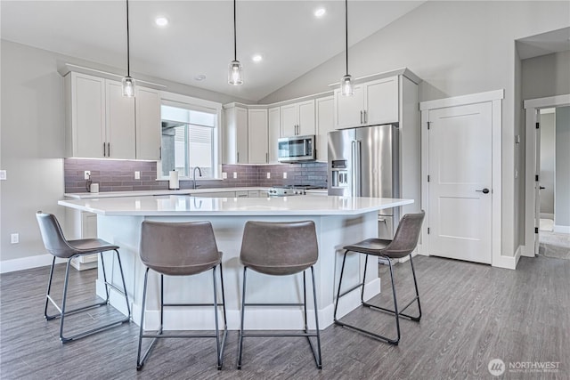 819 N Newport Loop, East Wenatchee, WA 98802 - kitchen with stainless steel appliances, baseboards, a kitchen island, light countertops, and lofted ceiling