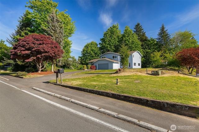 view of front of home featuring a front yard, asphalt driveway, and a garage