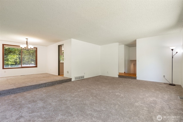 unfurnished living room featuring a chandelier, a textured ceiling, carpet, and baseboards