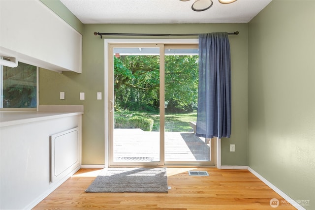 doorway featuring wood finished floors and baseboards
