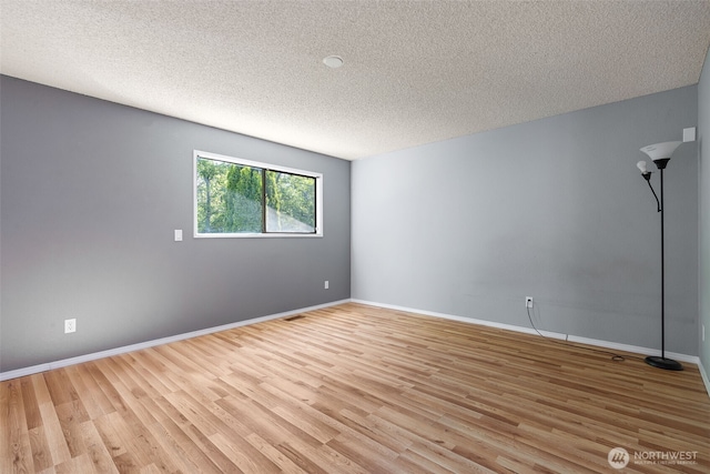unfurnished room featuring a textured ceiling, light wood-type flooring, and baseboards