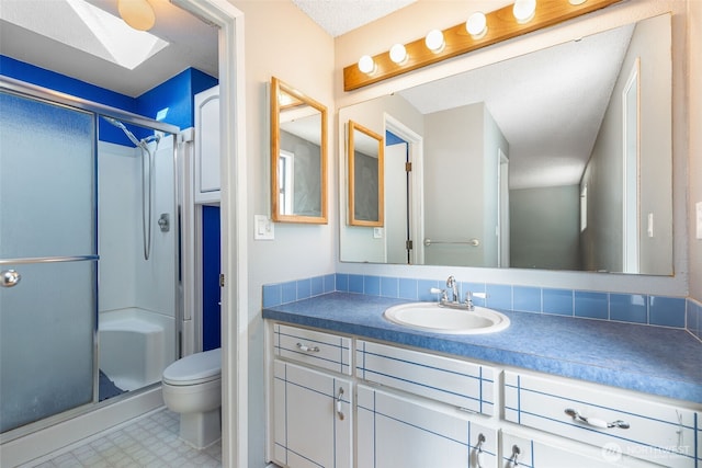 full bath with a skylight, a stall shower, vanity, and toilet