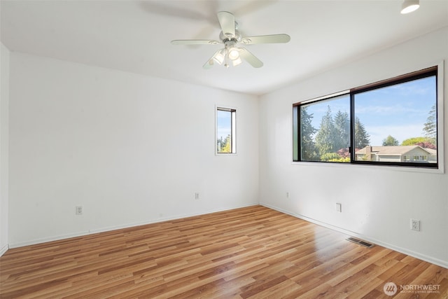 spare room with a ceiling fan, light wood-style flooring, and baseboards