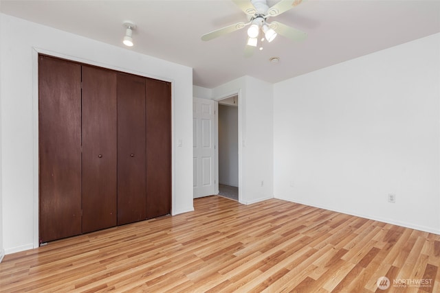 unfurnished bedroom featuring light wood-type flooring, a closet, a ceiling fan, and baseboards