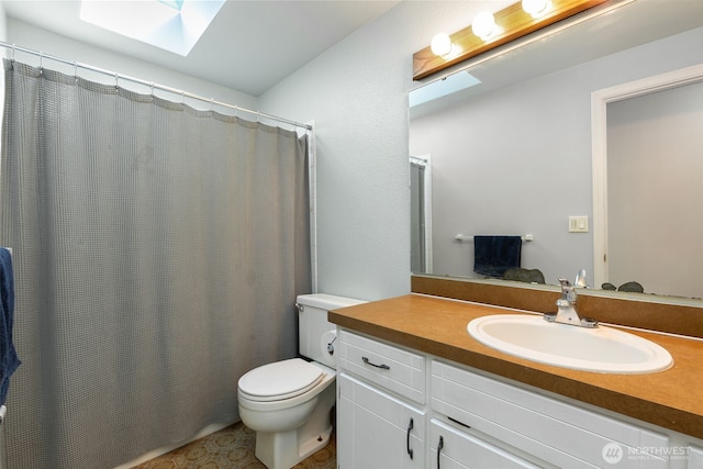 bathroom featuring a skylight, toilet, vanity, and a shower with curtain