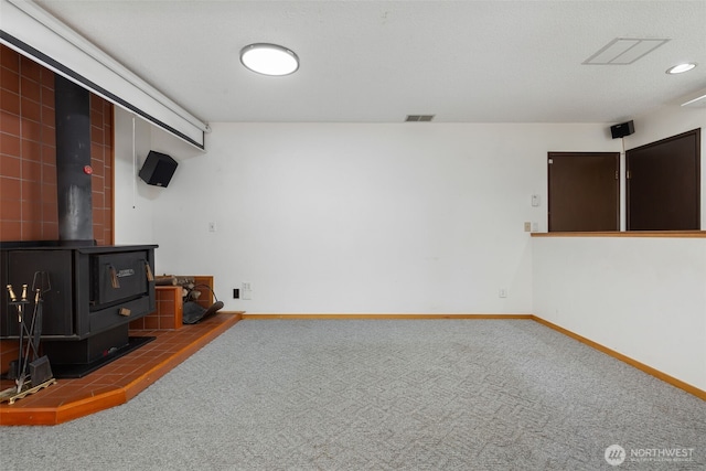 unfurnished living room with a wood stove, carpet floors, baseboards, and recessed lighting