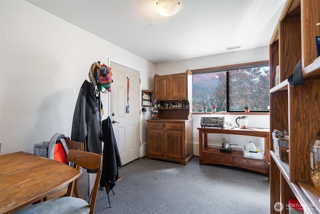 kitchen featuring light colored carpet and brown cabinets