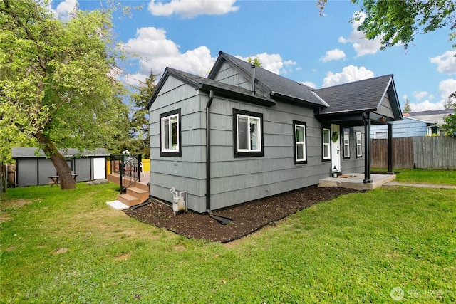 back of house with a storage shed, an outdoor structure, and roof with shingles