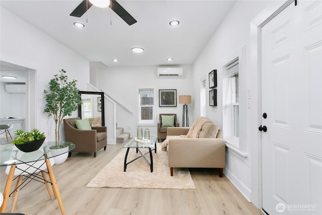living room with a wall mounted AC, stairway, light wood-type flooring, a ceiling fan, and recessed lighting