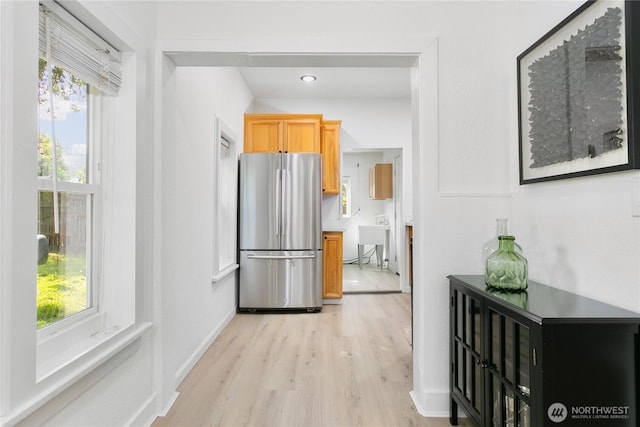 corridor featuring light wood finished floors and baseboards